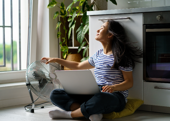 Girl staying cool with fan in front of windows