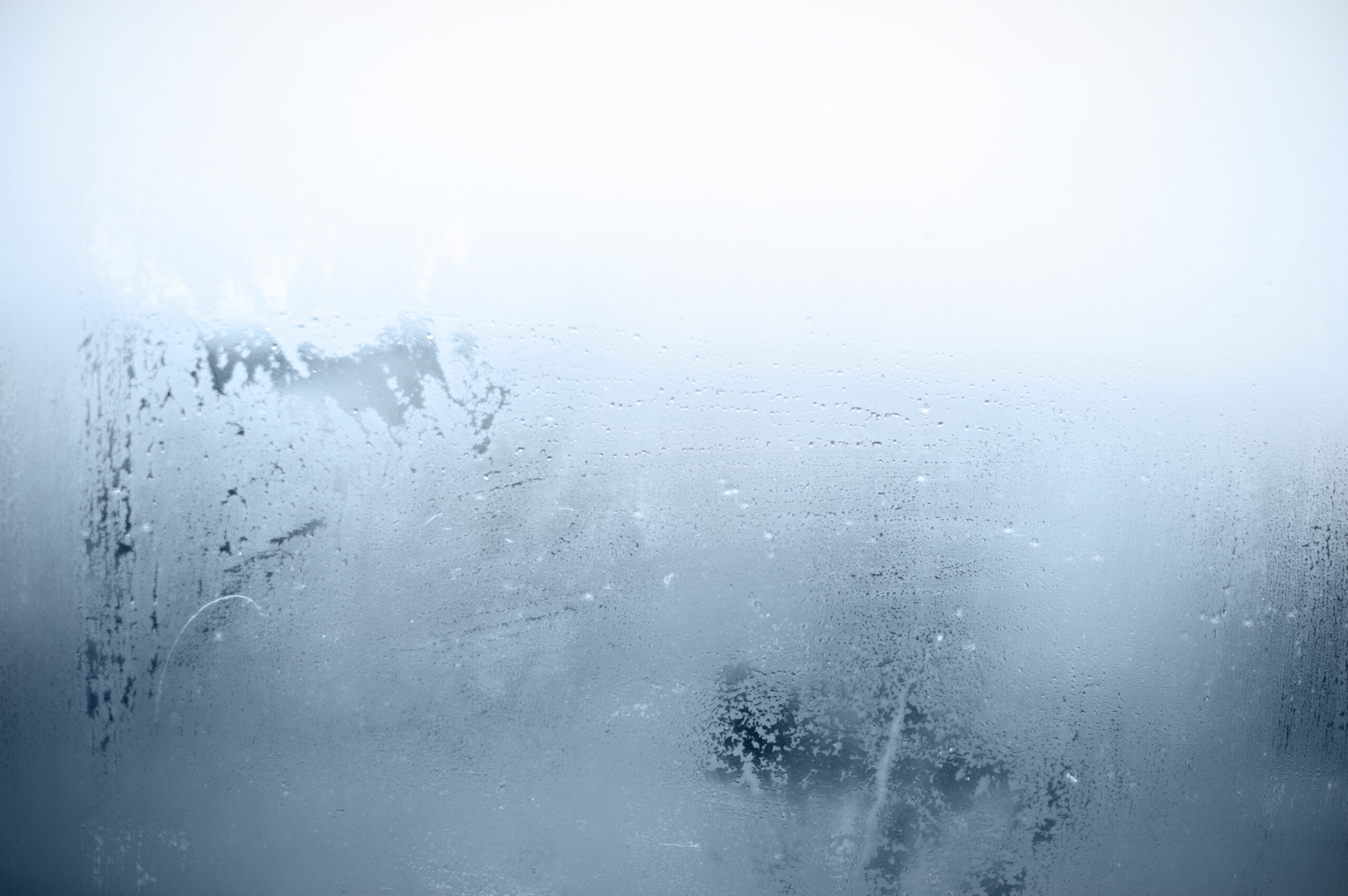 Foggy window with flowing water droplets.